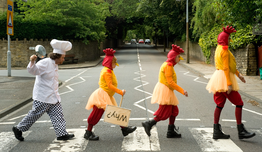 Picture of 4 people dressed as a chef and chickens on a zebra crossing