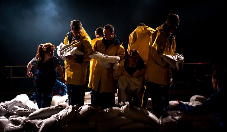 Men in yellow coats lifting sandbags
